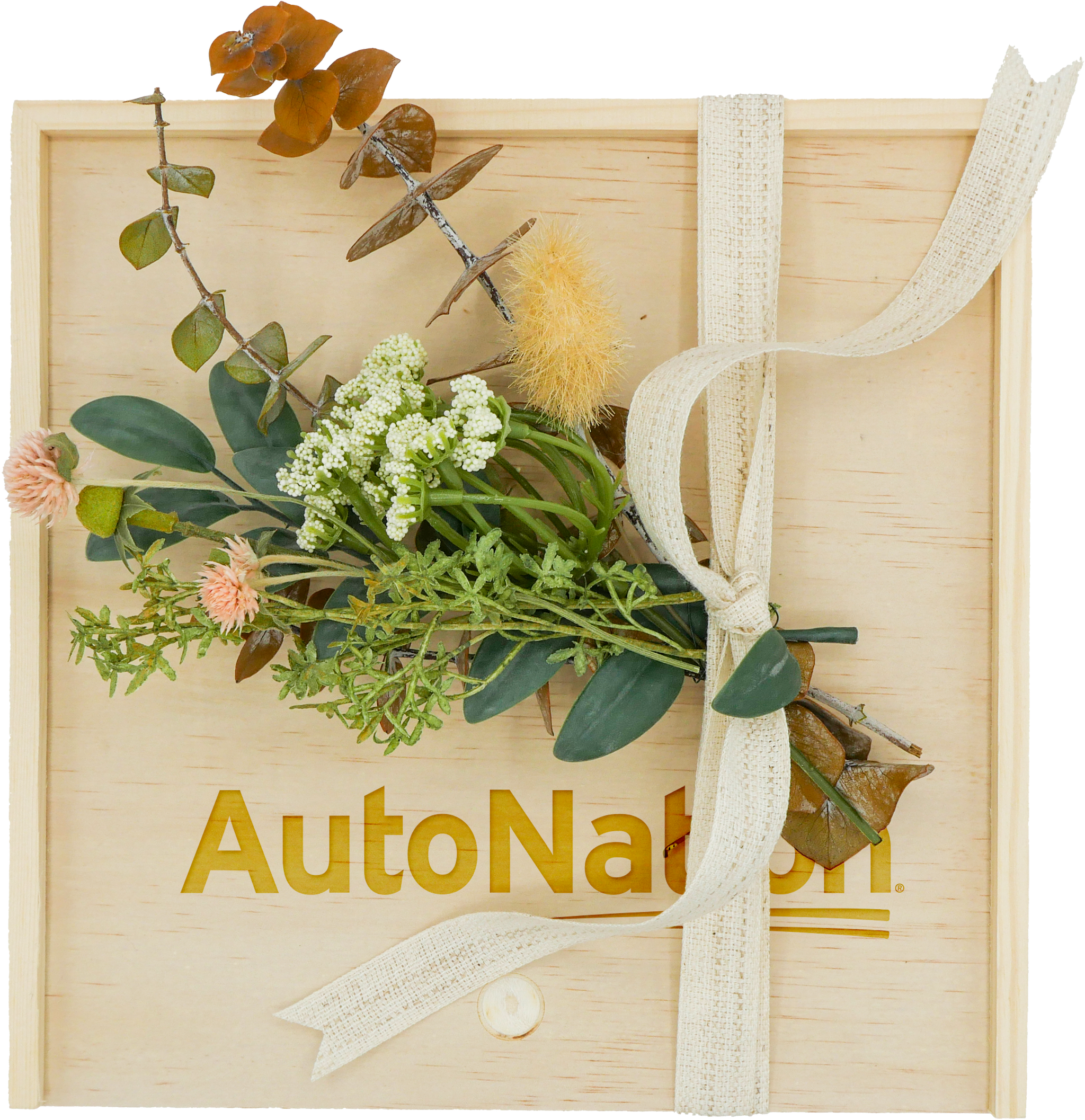 A previous AutoNation gift with a logo engraved on a wooden keepsake box, finished with ribbon and foliage